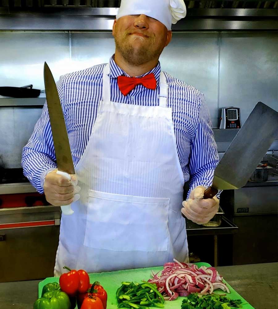 a Burrachos team member smiling about to cut veggies